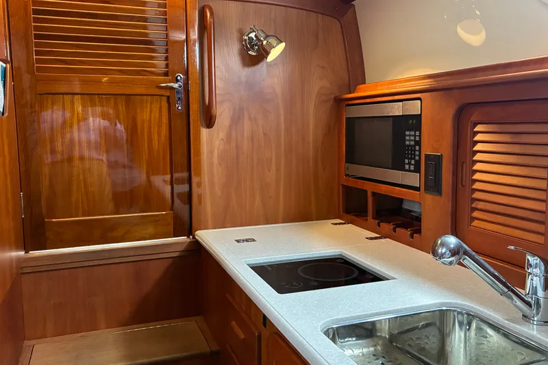 Slide: The Image of Hinckley Picnic Boat 37 MKIII 2014 interior kitchen with wooden cabinetry and modern appliances. - 33