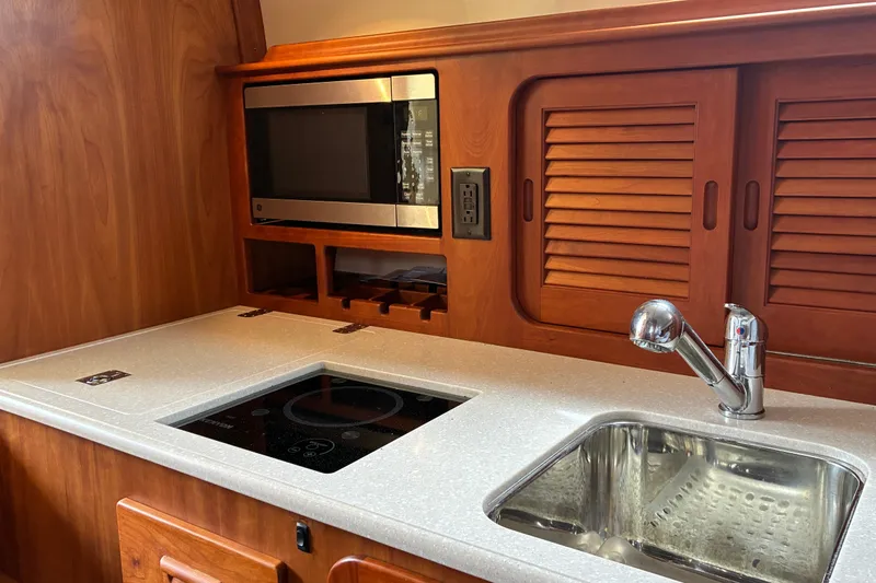 Slide: The Image of Hinckley Picnic Boat 37 MKIII 2014 galley with microwave, sink, and wooden cabinetry. - 31