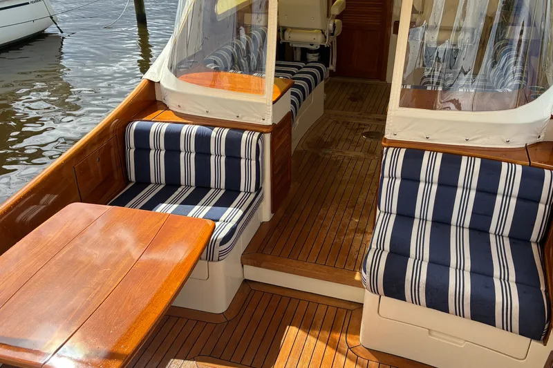 Slide: The Image of 2014 Hinckley Picnic Boat 37 MKIII interior with striped seating and wooden table. - 13
