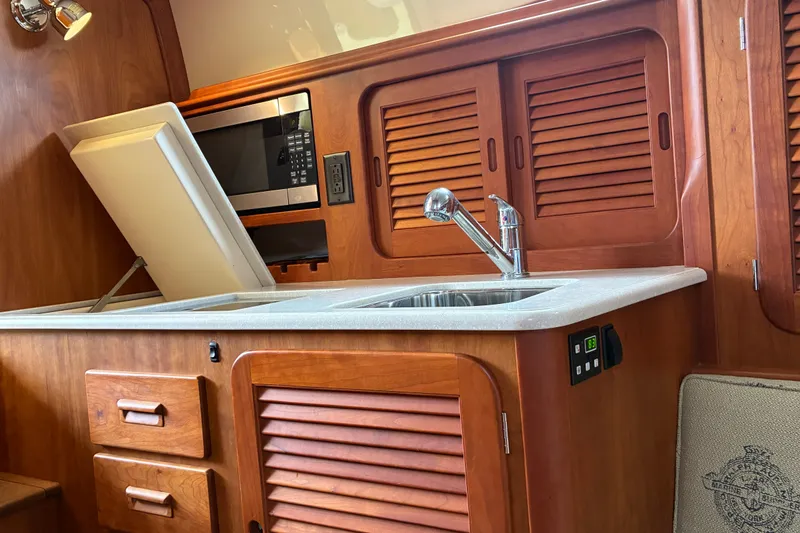 Slide: The Image of Hinckley Picnic Boat 37 MKIII 2014 interior with wooden cabinetry and modern kitchen amenities. - 32