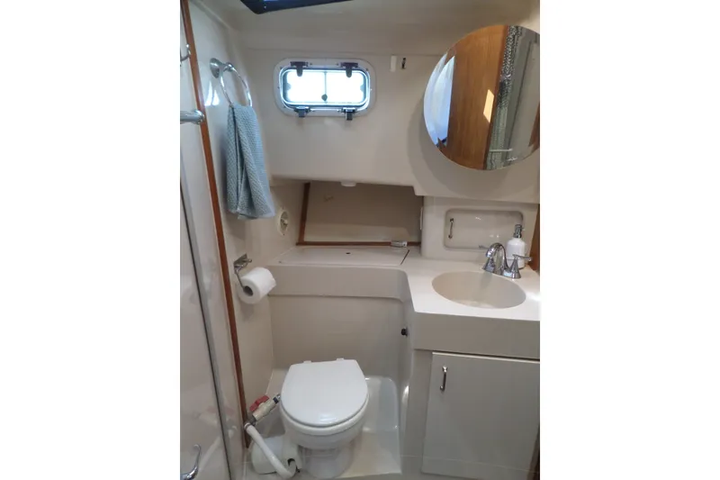 Slide: The Image of 1997 Mainship 350 Trawler bathroom with toilet, sink, mirror, and towel rack. - 27