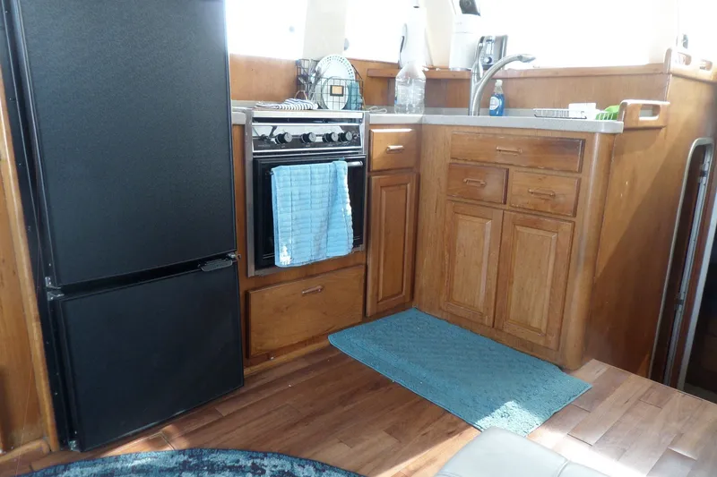 Slide: The Image of 1997 Mainship 350 Trawler kitchen with wooden cabinets, stove, and refrigerator. - 37