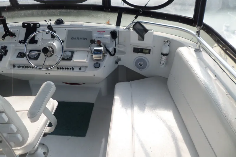 Slide: The Image of 1997 Mainship 350 Trawler helm with Garmin navigation, steering wheel, and seating area. - 75