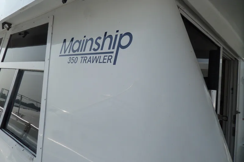 Slide: The Image of 1997 Mainship 350 Trawler boat exterior with logo and windows. - 90