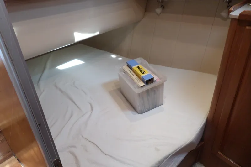 Slide: The Image of 1997 Mainship 350 Trawler cabin interior with bed and storage box. - 19