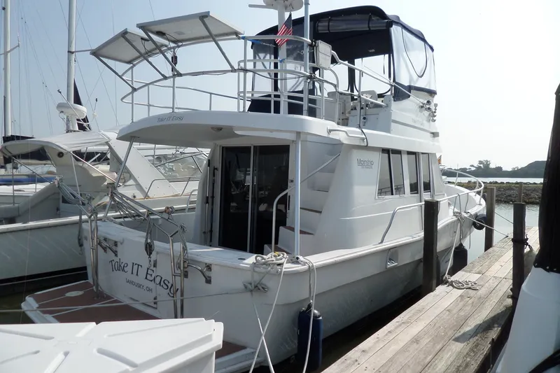 The Image of 1997 Mainship 350 Trawler docked, featuring upper deck and solar panels. - 0