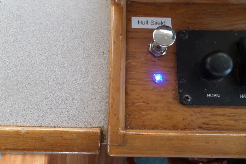 Slide: The Image of Control panel of a 1997 Mainship 350 Trawler with illuminated blue light and switch. - 46