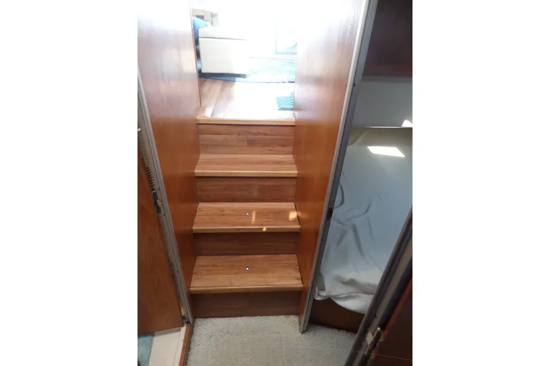 Slide: The Image of Wooden stairs inside a 1997 Mainship 350 Trawler, leading to a sunlit cabin area. - 32