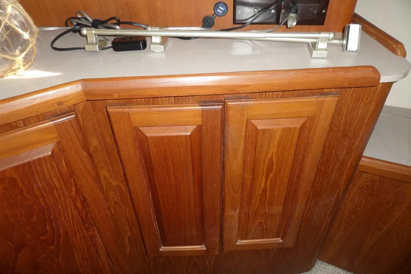 Slide: The Image of Wooden cabinetry inside a 1997 Mainship 350 Trawler boat, featuring a countertop and lamp. - 23