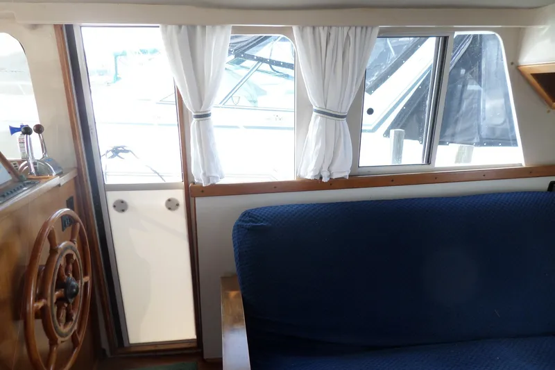 Slide: The Image of Interior of 1997 Mainship 350 Trawler with blue seating and wooden steering wheel. - 48
