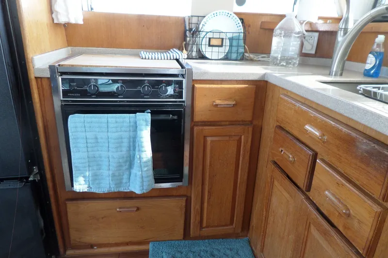 Slide: The Image of Kitchen area of 1997 Mainship 350 Trawler with stove, wooden cabinets, and countertop. - 38