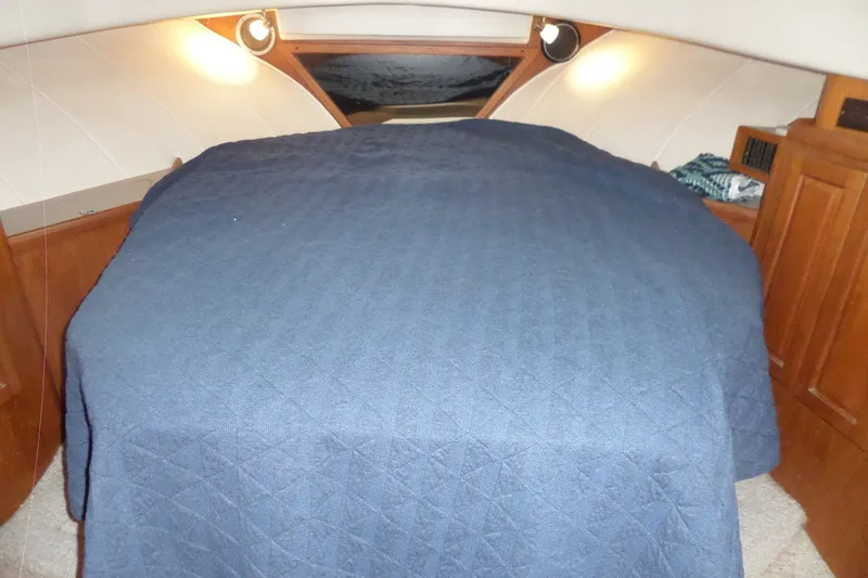 Slide: The Image of Cozy cabin interior of 1997 Mainship 350 Trawler with blue bedding and wooden accents. - 33