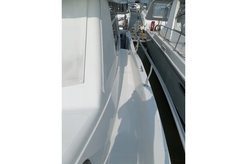 Slide: The Image of 1997 Mainship 350 Trawler side deck with railing, docked beside another boat. - 59