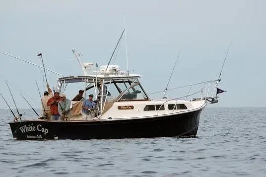 Slide: The Image of 1997 Fortier 33 boat named "White Cap" on the water with people fishing. - 2