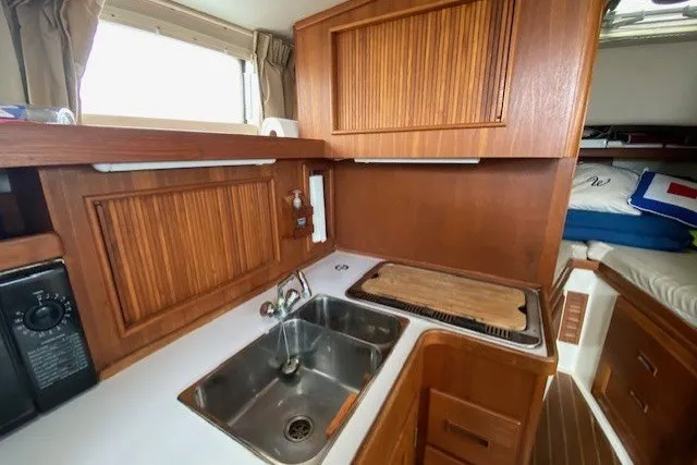 Slide: The Image of 1997 Fortier 33 boat interior with wooden cabinetry, stainless steel sink, and compact kitchen area. - 16