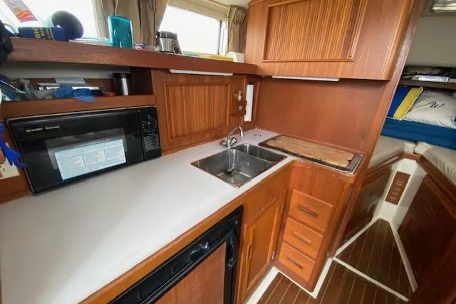 Slide: The Image of 1997 Fortier 33 boat interior kitchen with wooden cabinets, sink, and microwave. - 9
