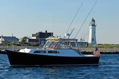 The Image of Fortier 33 boat from 1997 on water near a lighthouse, American flag displayed. - 1