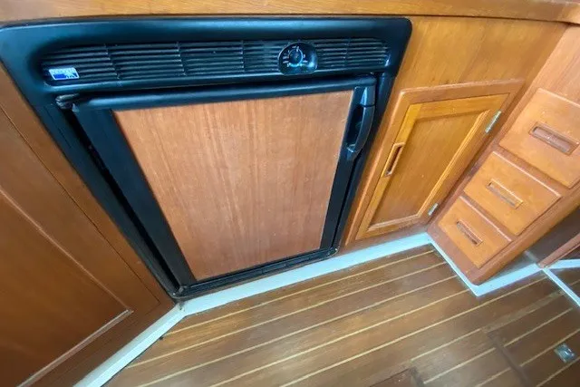 Slide: The Image of 1997 Fortier 33 boat interior with wooden cabinetry and compact refrigerator. - 6