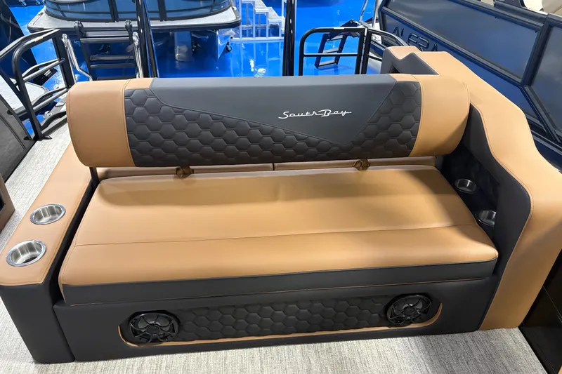 Slide: The Image of 2027 South Bay 525UL boat seat with tan and black upholstery, featuring cup holders and speakers. - 12