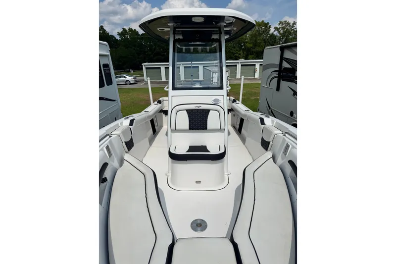 Slide: The Image of 2022 Tidewater 232 LXF boat interior with seating and console, parked outdoors. - 4