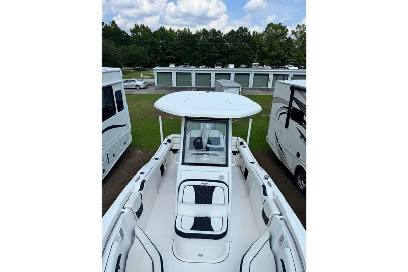 Slide: The Image of 2022 Tidewater 232 LXF boat with T-top, parked between RVs, under a partly cloudy sky. - 3