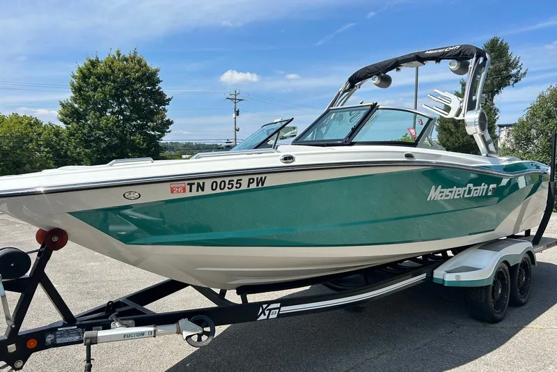 Slide: The Image of 2017 MasterCraft XT23 boat on trailer, teal and white design, parked outdoors. - 5