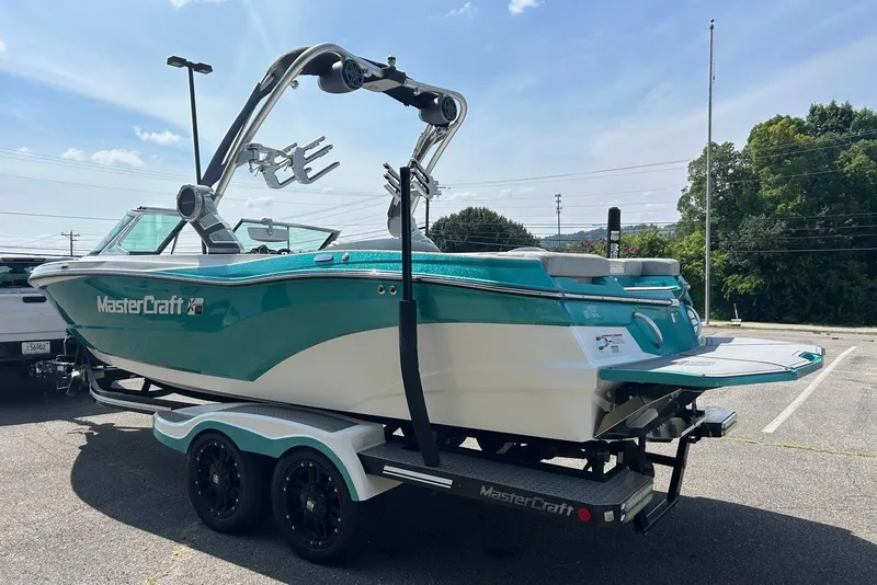 Slide: The Image of 2017 MasterCraft XT23 boat on trailer, teal and white design, parked outdoors. - 4