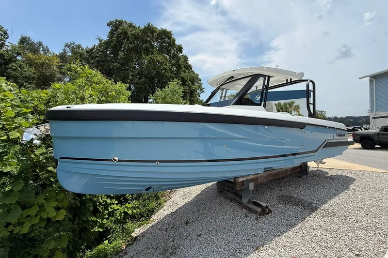 Slide: The Image of A 2026 Wellcraft 28 T-Top boat on a gravel lot. It features a light blue hull. - 0