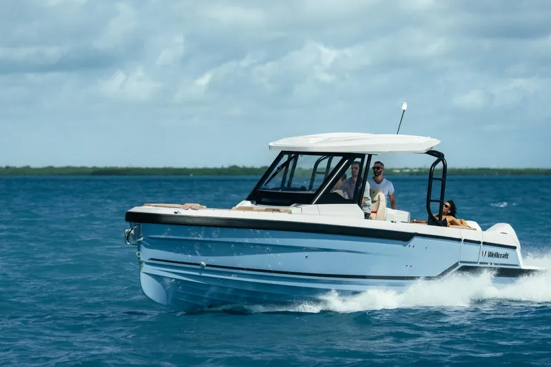 The Image of 2026 Wellcraft 28 T-Top boat cruising on open water under a cloudy sky. - 5