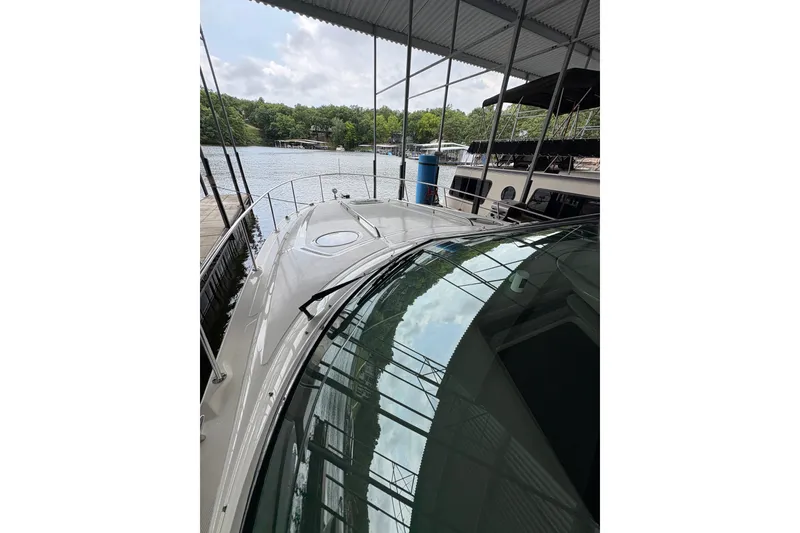Slide: The Image of 2006 Sea Ray 340 Sundancer docked under a covered marina with scenic lake view. - 34