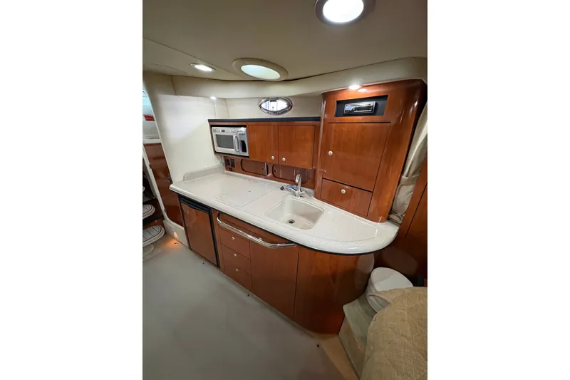 Slide: The Image of 2006 Sea Ray 340 Sundancer yacht interior with kitchenette, featuring wood cabinetry and modern appliances. - 23