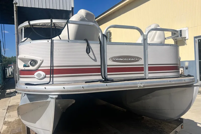 Slide: The Image of 2006 Princecraft Versailles 22 LP-SS pontoon boat with red stripe, docked outdoors. - 2