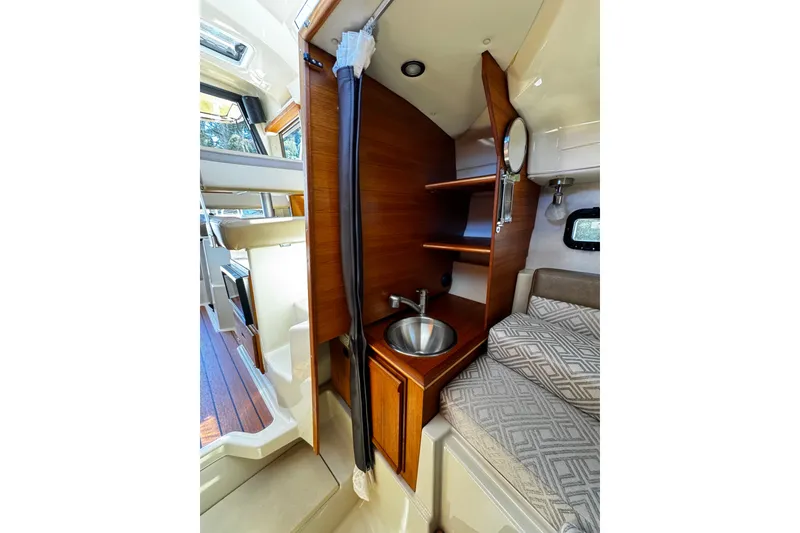 Slide: The Image of 2020 Ranger Tugs R-23 interior with compact sink, wooden shelves, and cozy sleeping area. - 8