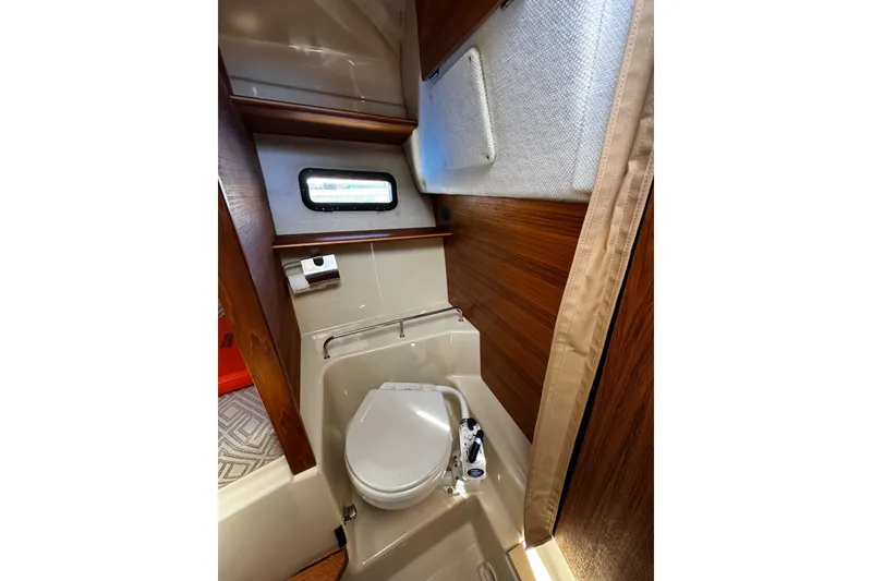 Slide: The Image of 2020 Ranger Tugs R-23 boat bathroom with compact toilet and wooden accents. - 9