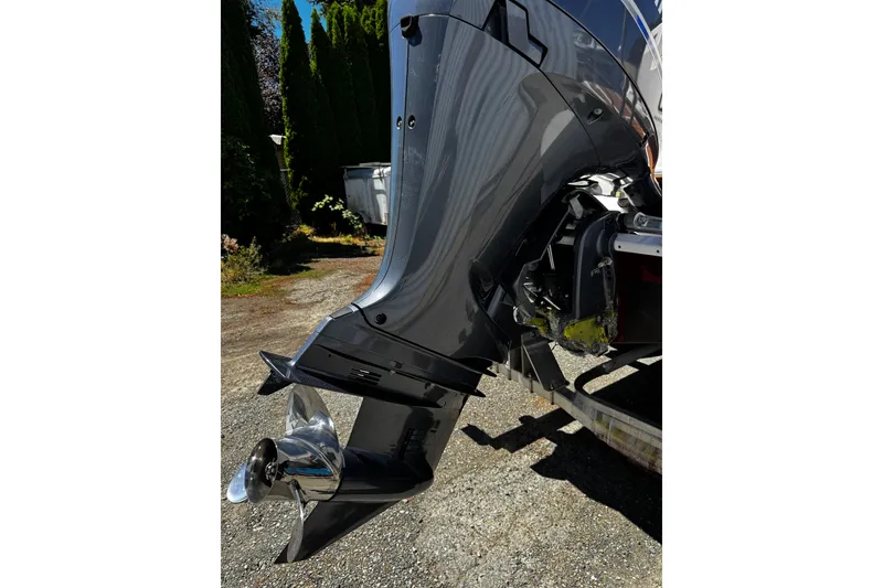 Slide: The Image of 2020 Ranger Tugs R-23 outboard motor with shiny propeller, parked on gravel. - 13