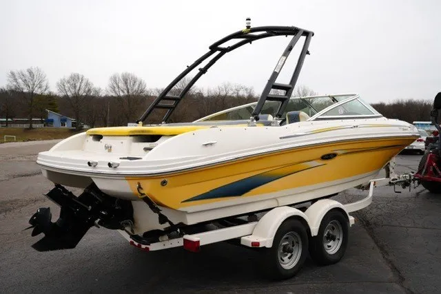 Slide: The Image of 2006 Sea Ray 205 Sport boat on trailer, yellow and white design, parked outdoors. - 11