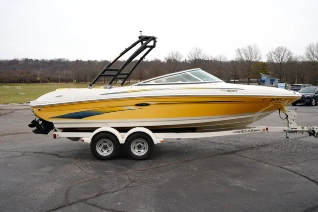 Slide: The Image of 2006 Sea Ray 205 Sport boat on trailer, yellow hull, parked outdoors. - 12