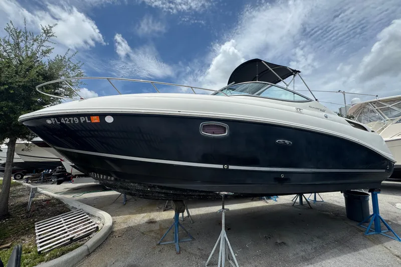 The Image of 2006 Sea Ray Sundancer 260 boat on stands under a cloudy sky. - 0