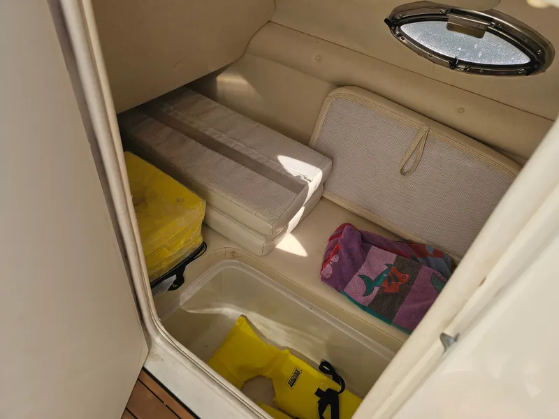 Slide: The Image of The interior of a 2006 Sea Ray 270 Sundeck shows storage space with towels and life jackets. - 28