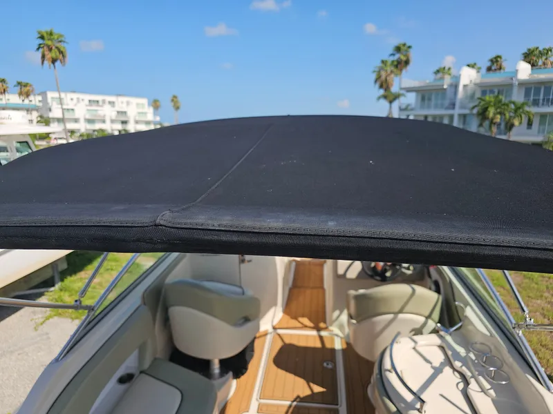 Slide: The Image of A 2006 Sea Ray 270 Sundeck with a black sunshade and wooden flooring, surrounded by palm trees. - 15