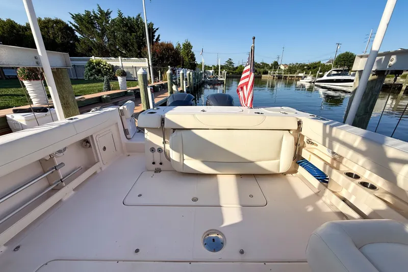 Slide: The Image of 2012 Grady-White Freedom 307 boat interior at a marina, featuring seating and American flag. - 18