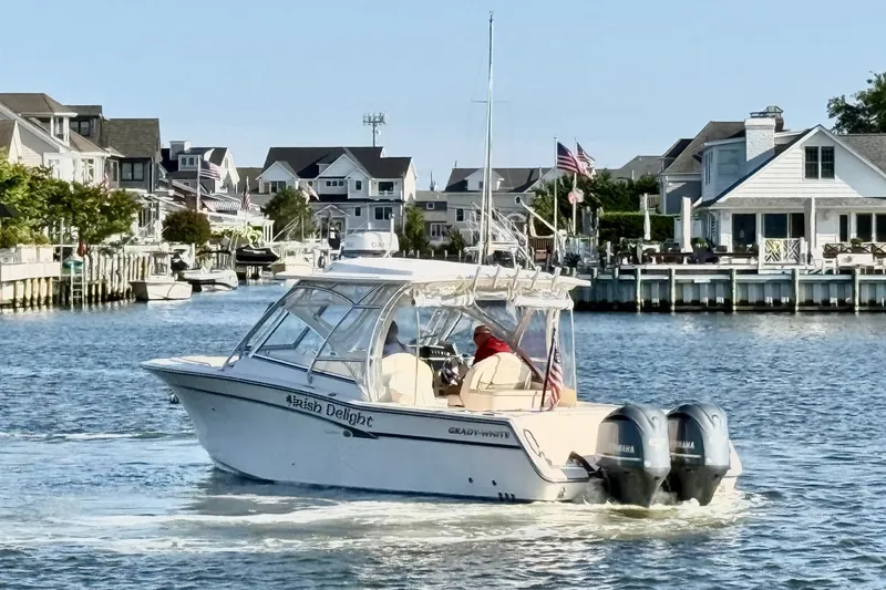 Slide: The Image of 2012 Grady-White Freedom 307 boat cruising in a residential waterfront area. - 10