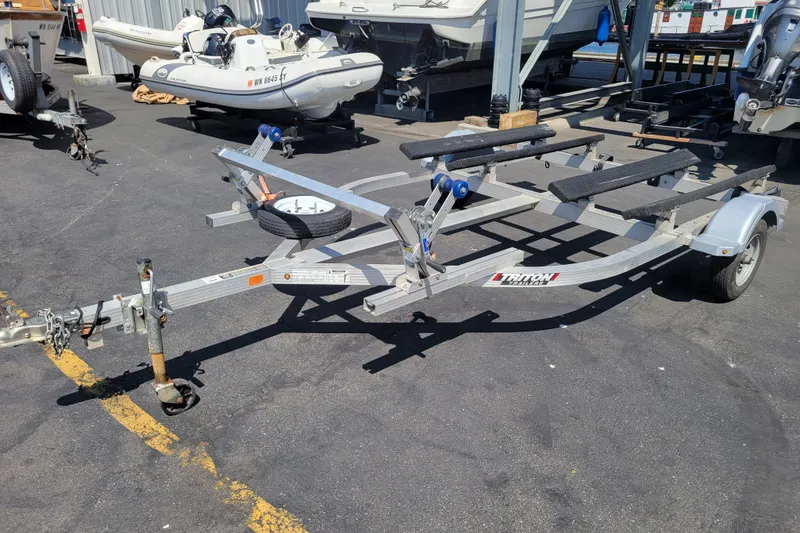 Slide: The Image of Boat trailer parked on asphalt, near various boats and equipment. - 24