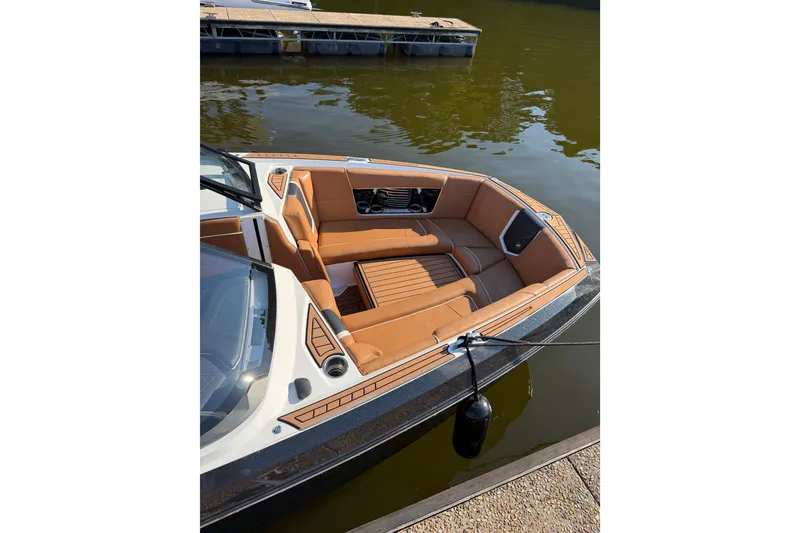 Slide: The Image of 2019 Nautique Super Air Nautique G25 boat with tan interior, docked on calm water. - 6