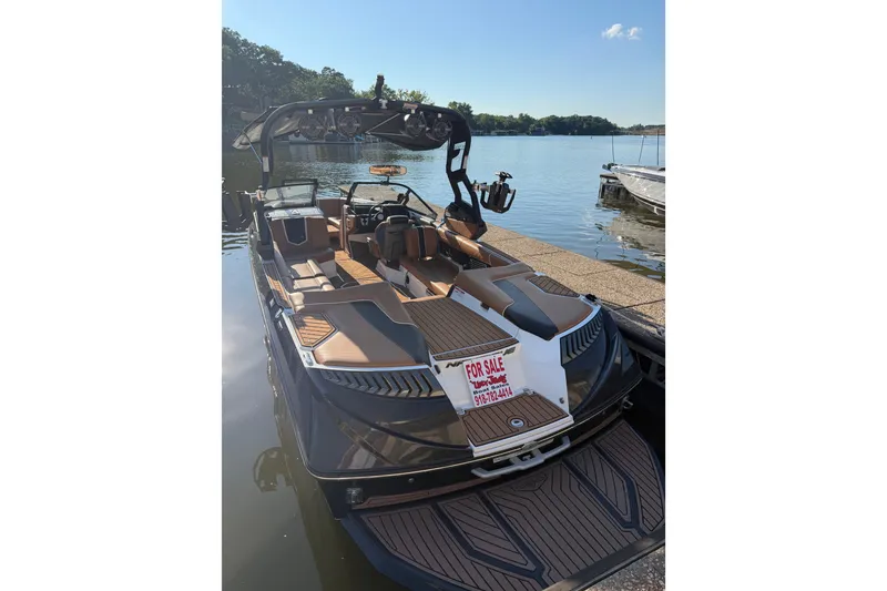 Slide: The Image of 2019 Nautique Super Air Nautique G25 boat for sale, docked by a serene lake. - 2