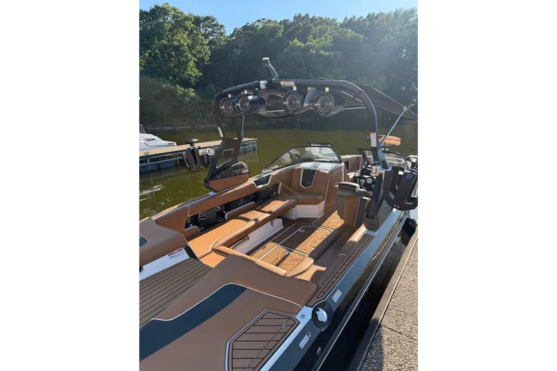 Slide: The Image of 2019 Nautique Super Air Nautique G25 boat with sleek interior design, docked by a lush shoreline. - 3