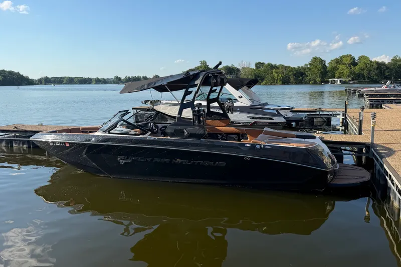 The Image of 2019 Nautique Super Air Nautique G25 boat docked on a serene lake. - 1