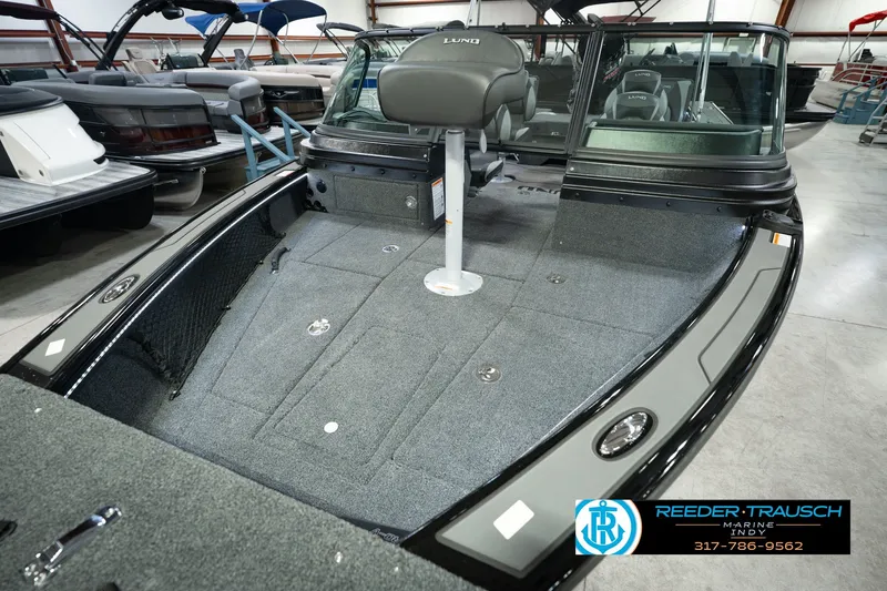 Slide: The Image of 2026 Lund 1975 Pro-V Sport boat interior with seating and carpeted deck in showroom. - 13