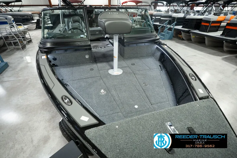 Slide: The Image of 2026 Lund 1975 Pro-V Sport boat interior with seating and carpeted deck in showroom. - 14