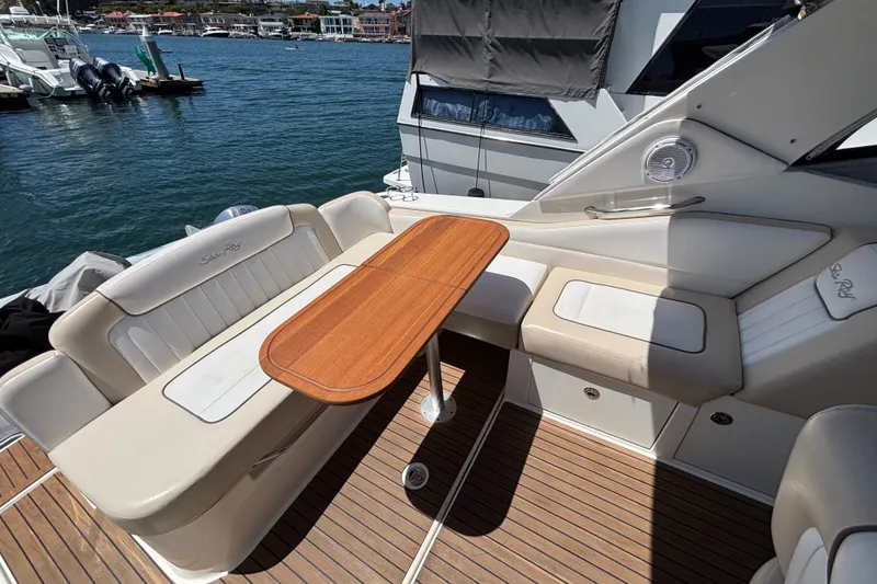 Slide: The Image of 2013 Sea Ray Sundancer 310 boat interior with seating and wooden table on deck. - 7